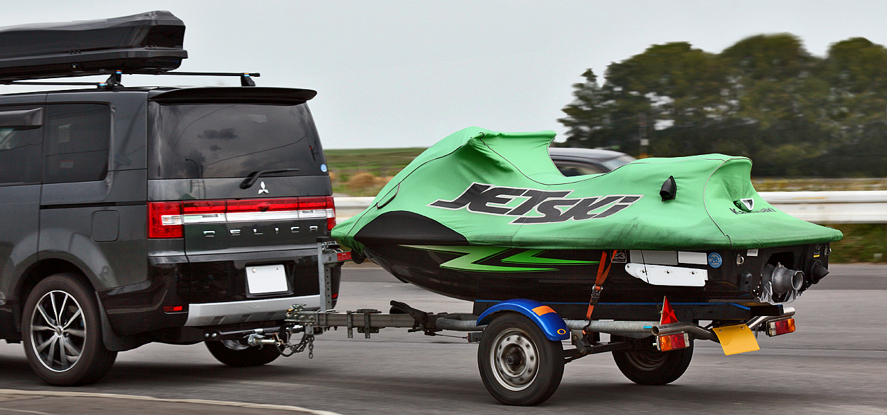 A Kawasaki Jet Ski on a trailer being towed behind a car